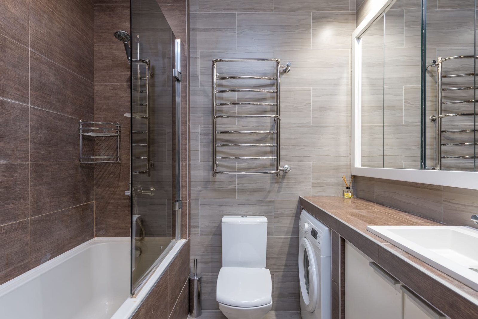 Ausgeführtes Badezimmer mit dunkler Holzoptik, heller Steinoptik und Badewanne mit Duschwand